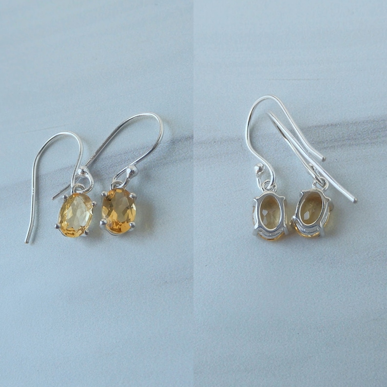 Peut inclure: Une paire de boucles d'oreilles pendantes en argent avec des pierres pr&eacute;cieuses en topaze de forme ovale. Les boucles d'oreilles ont un design simple et sont parfaites pour un usage quotidien.