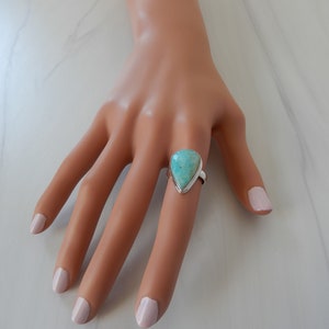 May include: A teardrop-shaped turquoise gemstone ring set in sterling silver.