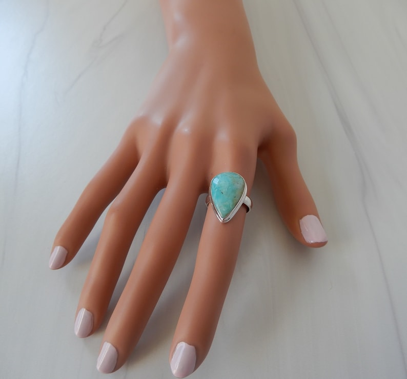 May include: A teardrop-shaped turquoise gemstone ring set in sterling silver.