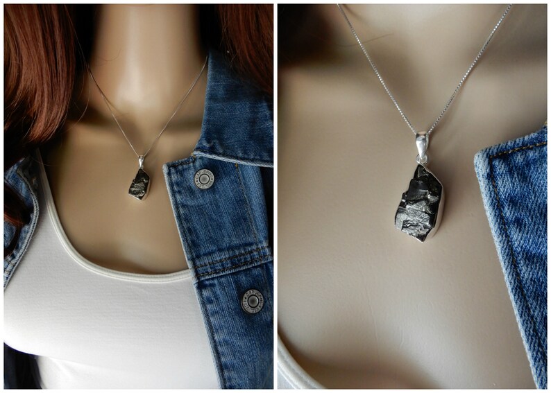 May include: A silver chain necklace with a raw, black, natural stone pendant. The pendant is a rough, irregular shape.
