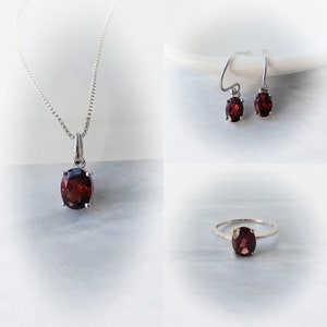 Pu&ograve; includere: Un set di gioielli in granato con una collana con ciondolo, orecchini e un anello. Ogni pezzo presenta una pietra preziosa di granato rosso di forma ovale incastonata in argento.