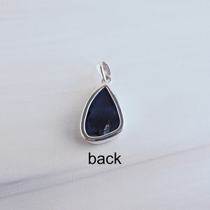 May include: Back view of a silver pendant with a black teardrop-shaped stone. The pendant has a bail for attaching to a chain.