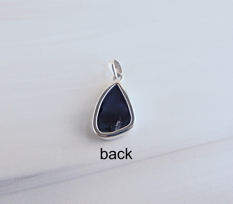 May include: Back view of a silver pendant with a black teardrop-shaped stone. The pendant has a bail for attaching to a chain.