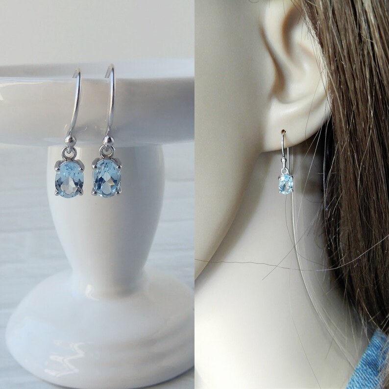 May include: A pair of silver dangle earrings with light blue oval-shaped gemstones.