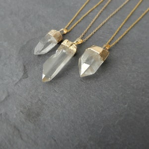 Puede incluir: Tres collares de oro con colgantes de cristal de cuarzo transparente. Los colgantes son de diferentes tama&ntilde;os y formas, y las cadenas son todas de la misma longitud.