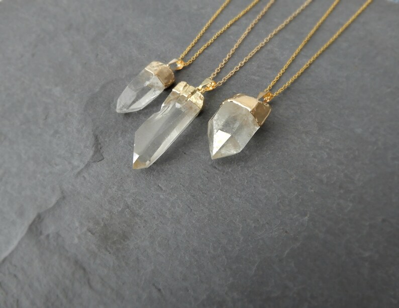 Puede incluir: Tres collares de oro con colgantes de cristal de cuarzo transparente. Los colgantes son de diferentes tama&ntilde;os y formas, y las cadenas son todas de la misma longitud.