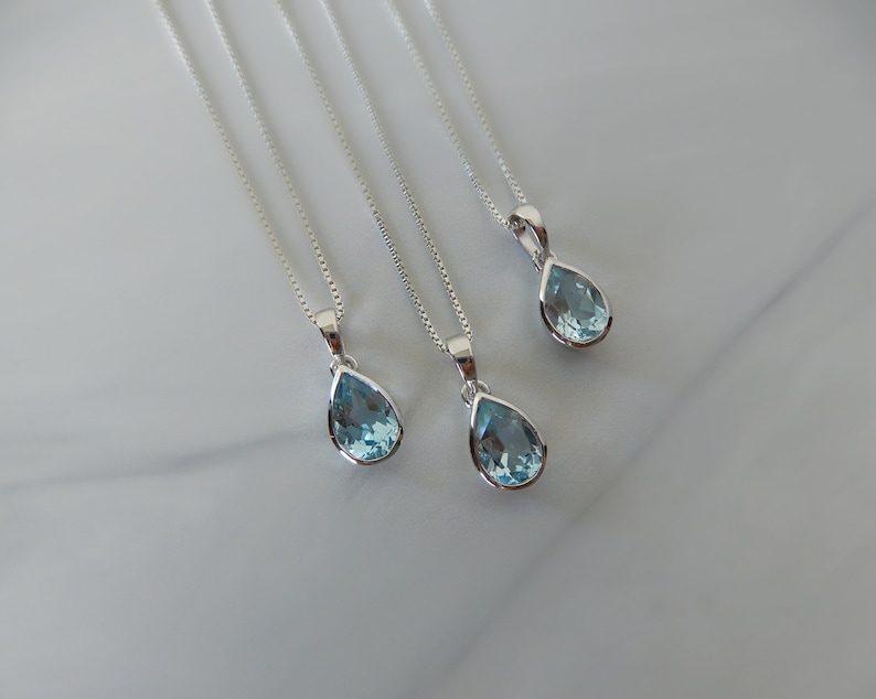 May include: Four silver necklaces with teardrop-shaped blue topaz pendants.