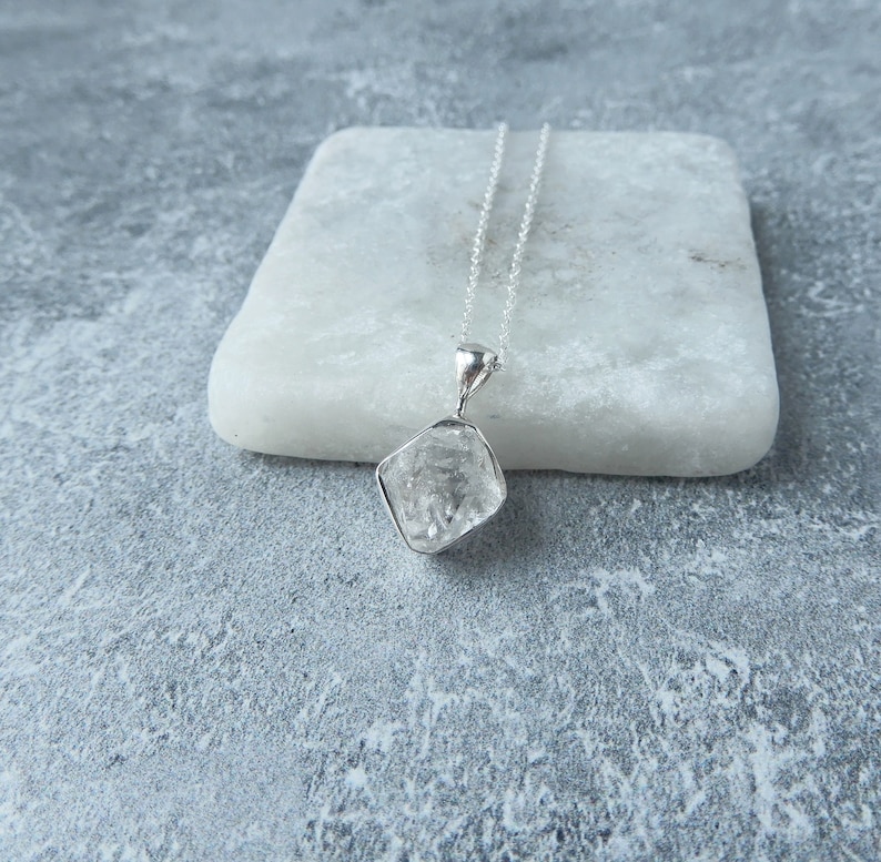 May include: A silver chain necklace with a clear, faceted crystal pendant.