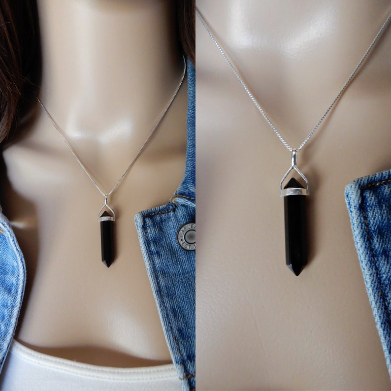 May include: A silver chain necklace with a black gemstone pendant in the shape of a point. The pendant is set in a silver bezel.