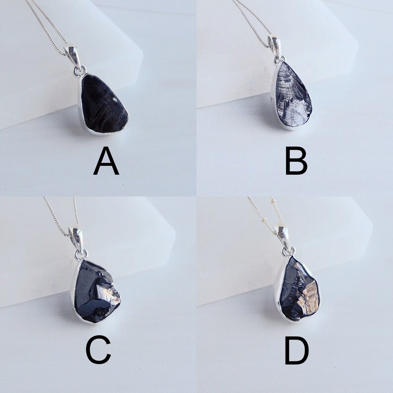 May include: Four silver necklaces with black teardrop-shaped pendants. The pendants have different patterns and textures. The necklaces are labeled A, B, C, and D.