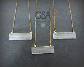 May include: Three gold necklaces with a white selenite bar pendant. Each necklace features a delicate gold chain.