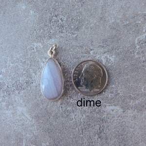 K&ouml;nnte beinhalten: Ein tropfenf&ouml;rmiger Anh&auml;nger mit einem hellblauen und wei&szlig;en Achat-Stein, der in Sterlingsilber gefasst ist. Der Anh&auml;nger wird neben einem US-Dime zum Gr&ouml;&szlig;envergleich gezeigt. "dime" steht unter der M&uuml;nze.