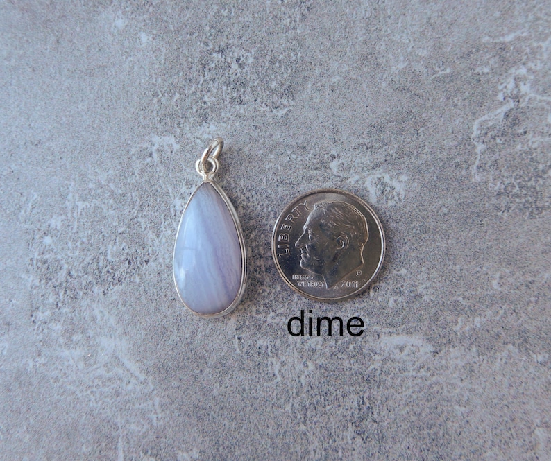 K&ouml;nnte beinhalten: Ein tropfenf&ouml;rmiger Anh&auml;nger mit einem hellblauen und wei&szlig;en Achat-Stein, der in Sterlingsilber gefasst ist. Der Anh&auml;nger wird neben einem US-Dime zum Gr&ouml;&szlig;envergleich gezeigt. "dime" steht unter der M&uuml;nze.