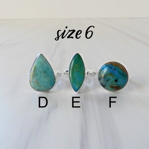 May include: Three silver rings with different turquoise gemstones. The rings are labeled D, E, and F. The text "size 6" is written above the rings.