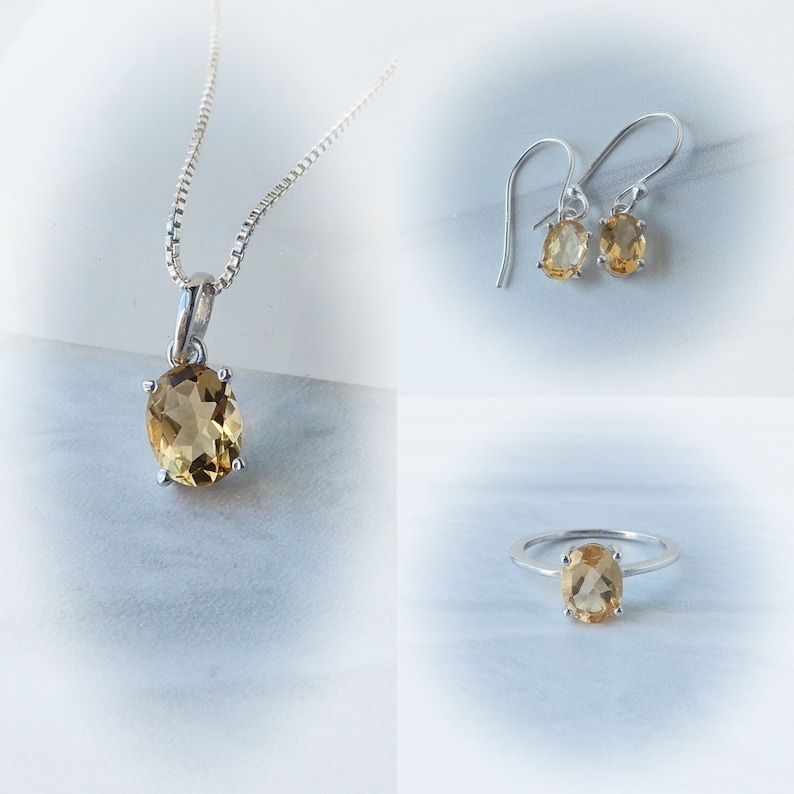 Peut inclure: Un ensemble de bijoux compos&eacute; d'un collier, de boucles d'oreilles et d'une bague en argent avec une pierre ovale brun clair.