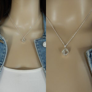 May include: A silver chain necklace with a clear, faceted, square-shaped crystal pendant.
