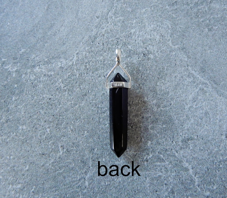 May include: Black obsidian crystal point pendant with a silver bail. The bail is marked with "925" for sterling silver. The back of the pendant is shown in the image.