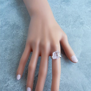 K&ouml;nnte beinhalten: Ein silberner Ring mit einem klaren, facettierten, rohen Kristallstein. Der Ring befindet sich an einem Modellfinger.
