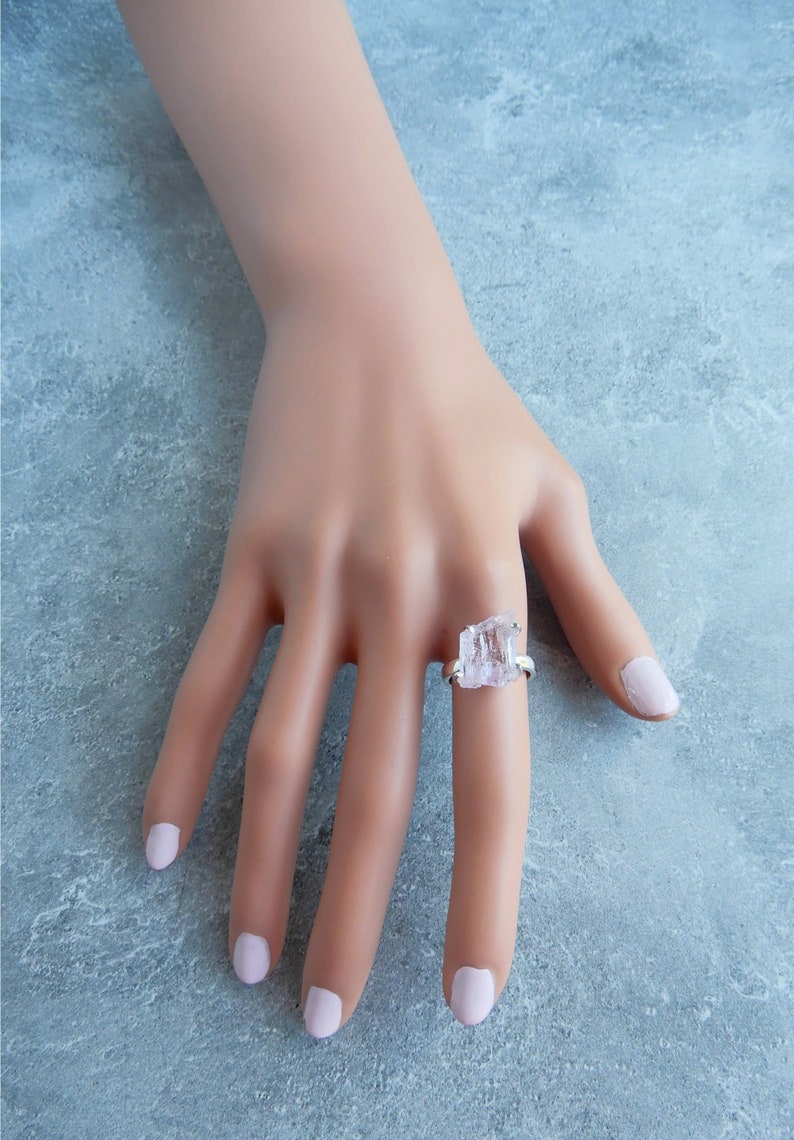 K&ouml;nnte beinhalten: Ein silberner Ring mit einem klaren, facettierten, rohen Kristallstein. Der Ring befindet sich an einem Modellfinger.