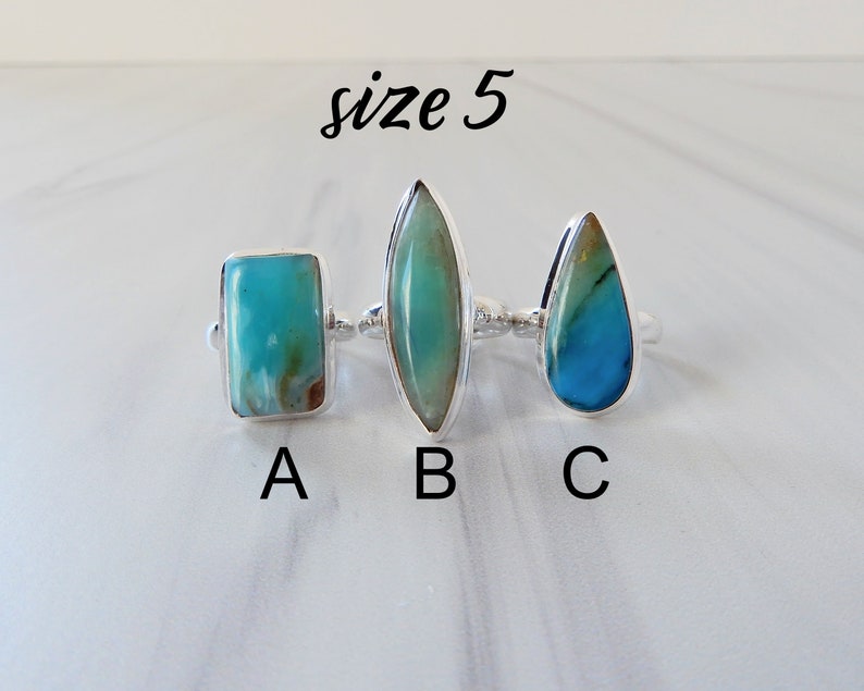 May include: Three silver rings with different shaped turquoise stones. The rings are labeled A, B, and C. The text "size 5" is written above the rings.