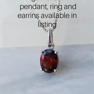 Pu&ograve; includere: Una collana con catena d'argento con un ciondolo con una pietra di granato rossa. Il testo "garnet set pendant, ring and earrings available in listing" &egrave; visibile sopra il ciondolo.