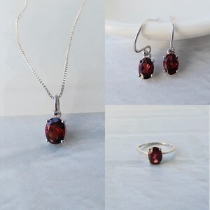 Pu&ograve; includere: Un set di gioielli in granato composto da una collana, orecchini e un anello. Ogni pezzo presenta una pietra preziosa di granato rossa di forma ovale incastonata in argento.
