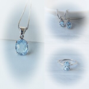 May include: A set of aquamarine jewelry featuring a necklace, earrings, and a ring. Each piece has a light blue oval-shaped gemstone.