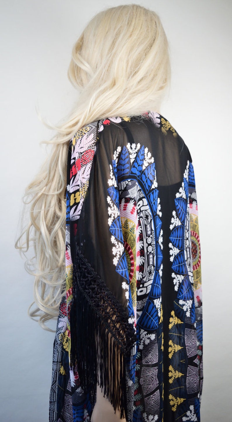 May include: Black sheer kimono with a colorful floral and geometric pattern. The kimono has black fringe trim on the sleeves.