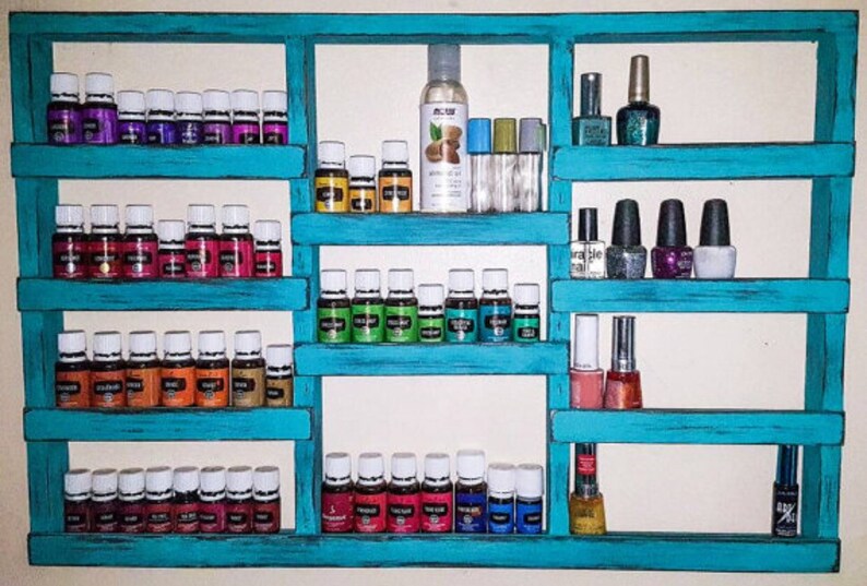 May include: Teal wooden shelf unit with five shelves, holding rows of small glass bottles and nail polish bottles.