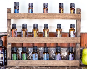 May include: A wooden shelf unit with three tiers holds multiple small amber glass bottles with black caps. The bottles are labeled "doterra" and have various essential oil names printed on them.