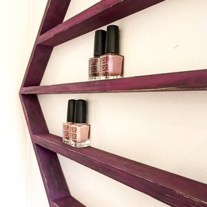 May include: Purple hexagonal wooden shelf with three shelves, displaying nail polish bottles. The bottles are clear with black caps and have the text "PEP PER POT" on the labels.
