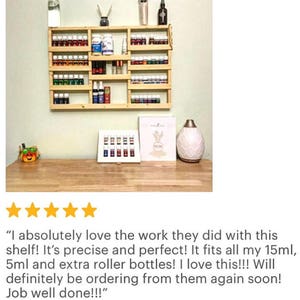 May include: A wooden wall-mounted shelf with multiple shelves for storing essential oil bottles. The shelf is filled with various sized bottles, including roller bottles. The shelf is made of natural wood and has a rustic look.