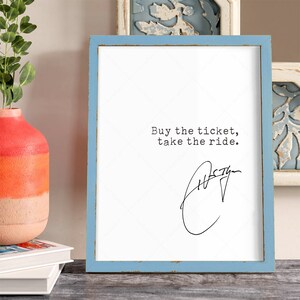 K&ouml;nnte beinhalten: Ein gerahmter Druck mit einem blauen Rahmen und wei&szlig;em Hintergrund. Der Druck zeigt den Text "Buy the ticket, take the ride." in schwarzer Schrift. Unter dem Text befindet sich eine handschriftliche Unterschrift.