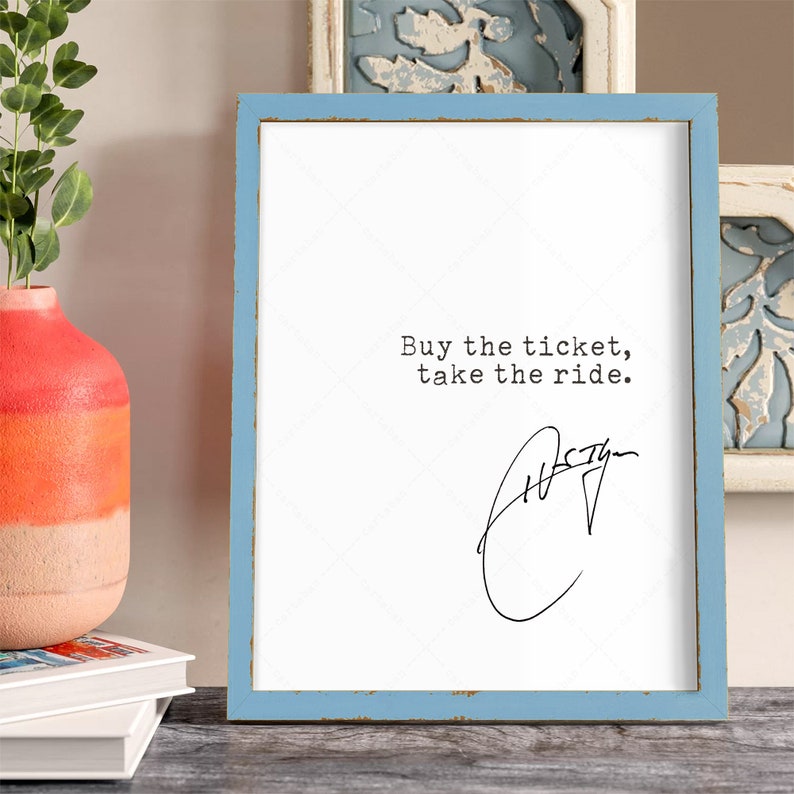 K&ouml;nnte beinhalten: Ein gerahmter Druck mit einem blauen Rahmen und wei&szlig;em Hintergrund. Der Druck zeigt den Text "Buy the ticket, take the ride." in schwarzer Schrift. Unter dem Text befindet sich eine handschriftliche Unterschrift.