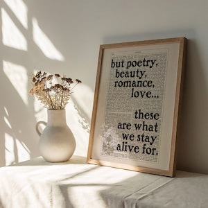 May include: A framed print with a white background and black text that reads "but poetry, beauty, romance, love... these are what we stay alive for."