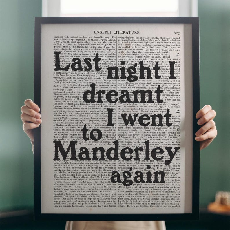 May include: A black framed print with a vintage book page background. The text on the page is in black and white. The text on the page reads "Last night I dreamt I went to Manderley again".