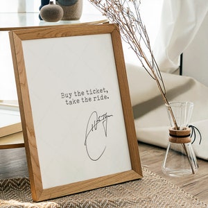 K&ouml;nnte beinhalten: Ein Holzrahmen mit dem Text "Buy the ticket, take the ride." und einer handschriftlichen Unterschrift.