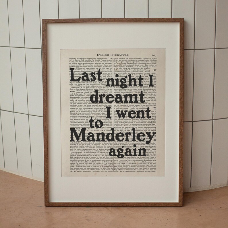 May include: A framed print of a book page with the text "Last night I dreamt I went to Manderley again" in bold black font.