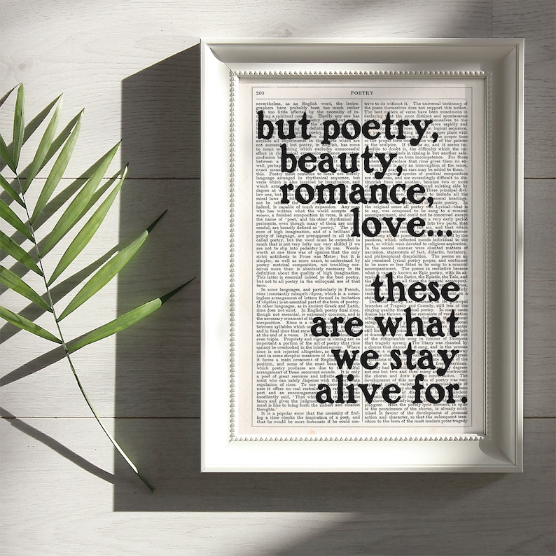 May include: A framed print with a black and white background featuring a quote from a book about poetry. The quote reads "but poetry, beauty, romance, love... these are what we stay alive for."