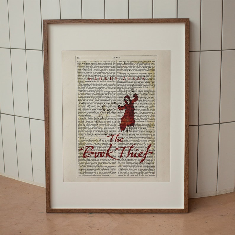 Pode incluir: Uma impress&atilde;o emoldurada de uma capa de livro com uma ilustra&ccedil;&atilde;o vermelha e preta de uma figura com uma t&uacute;nica com capuz segurando uma foice. O t&iacute;tulo do livro &eacute; "The Book Thief" em letras vermelhas.