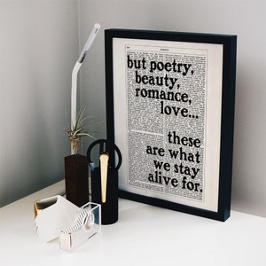 May include: Black and white framed print with a quote from a dictionary page. The quote reads "but poetry, beauty, romance, love... these are what we stay alive for."