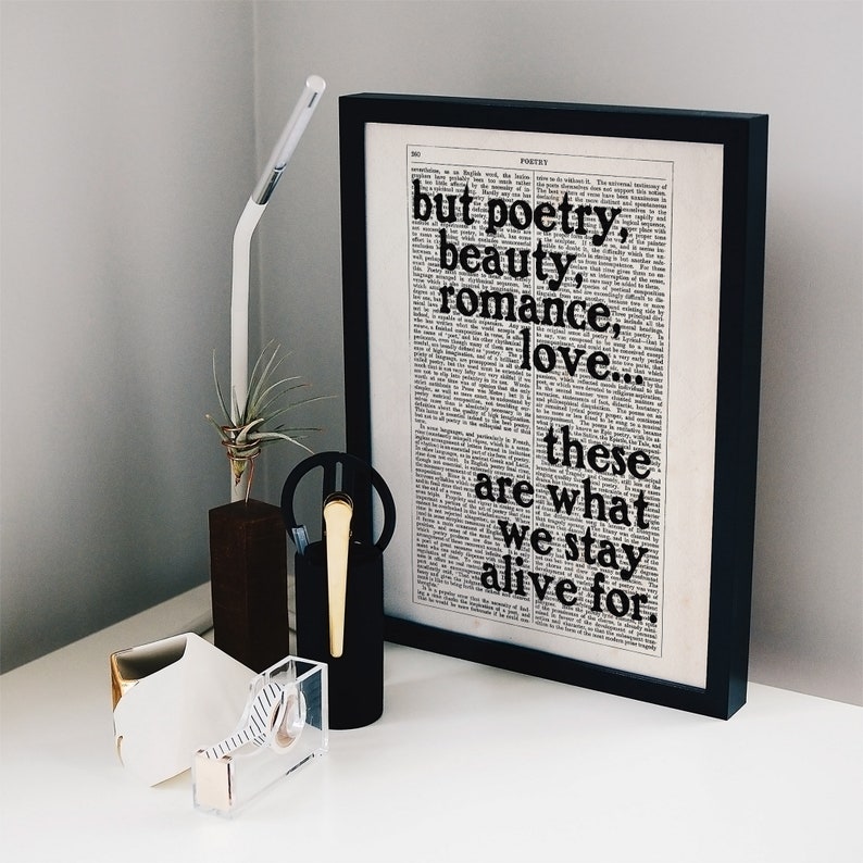 May include: Black and white framed print with a quote from a dictionary page. The quote reads "but poetry, beauty, romance, love... these are what we stay alive for."