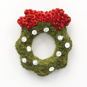 Op de afbeelding: Een groene kerstkrans van vilt met rode en zilveren pailletten.
