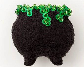 May include: A black felt cauldron with a green sequin trim. The cauldron is a Halloween decoration.