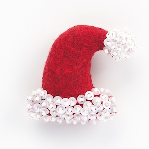 Peut inclure: Un chapeau de Père Noël en feutre rouge avec des paillettes blanches autour du bord et du haut.