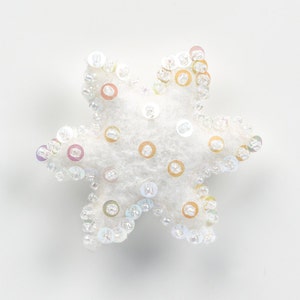 May include: A white felt star ornament decorated with iridescent sequins.