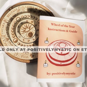 May include: A pink booklet with the title "Wheel of the Year Instructions & Guide" and the text "SOLD ONLY AT POSITIVELYMYSTIC ON ETSY" and "by: positivelymystic". The booklet features a red and white illustration of a wheel with concentric circles.