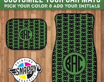 May include: Green car floor mats with a black cat pattern and a monogrammed circle in the center. The monogram reads "GAC". The mats are surrounded by a wooden surface.