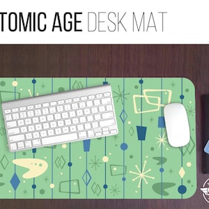 May include: A green desk mat with a retro atomic age design featuring blue, white, and yellow geometric shapes. The mat has a white keyboard and a white mouse on top of it.