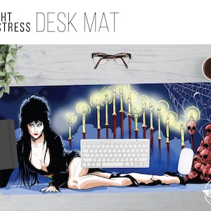 May include: A desk mat featuring a dark-haired woman with a black dress, lying on a bed of clouds with a row of lit candles behind her. The background is a dark blue with a spiderweb and skulls.
